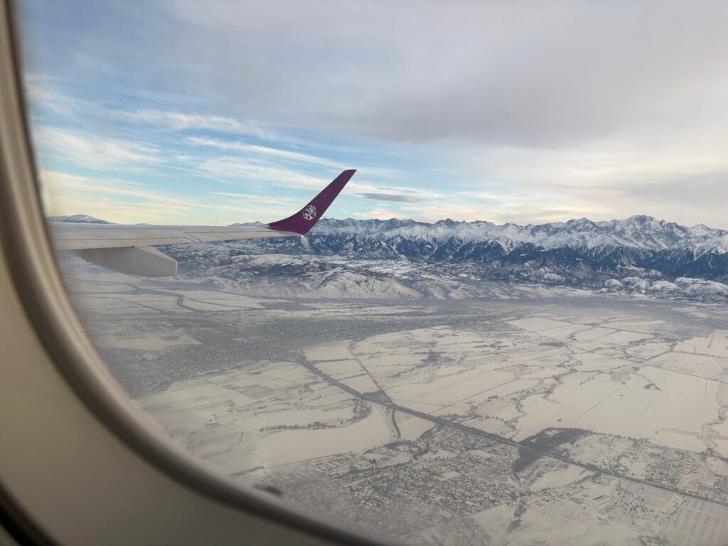 機内の窓から見た冬の天山山脈と雪に覆われた平野